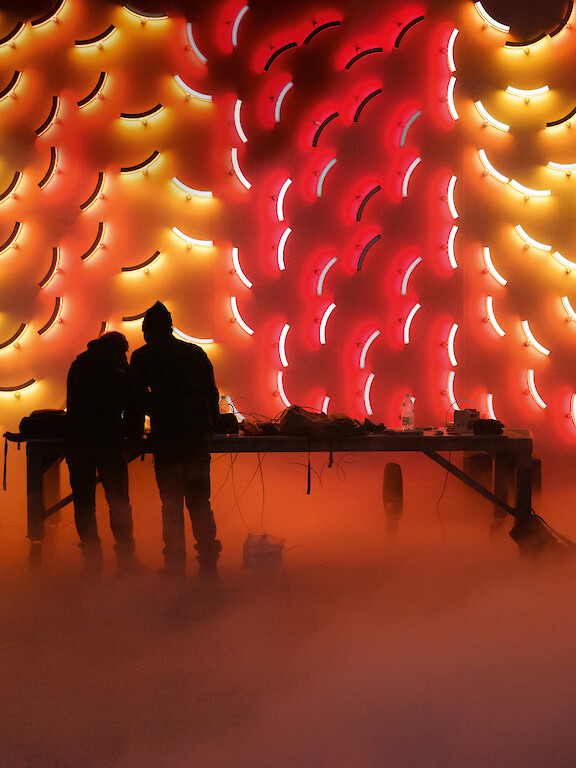 Two people in front of a wall of illuminated, colored circular segment