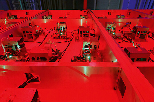 Electronic components and circuit boards on a workbench under intense red lighting.