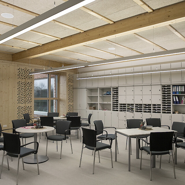 Bright school room with wood elements, flexible seating areas and long linear pendant lights