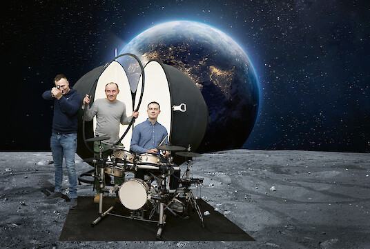Tres empleados de Lightnet con un luxómetro y una batería ante un escenario espacial.