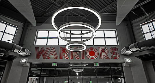 High school entrance with three ring-shaped pendant lights and large Warriors lettering on the wall