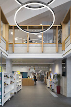 Open library area with bookshelves, gallery and distinctive ring-shaped pendant luminaires