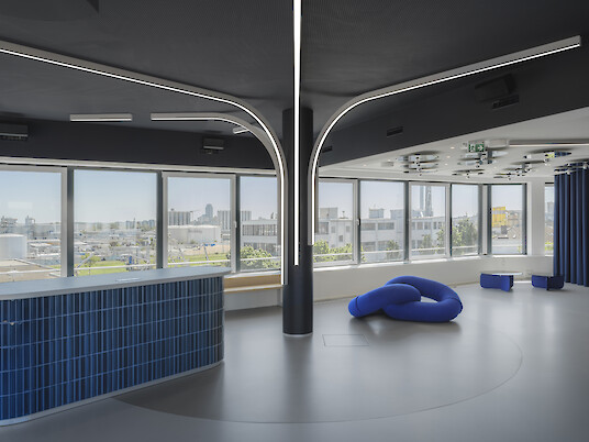 Modern interior with curved light lines, large windows and blue seating.