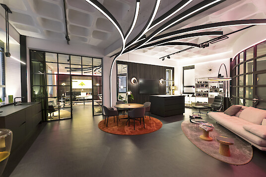 Modern lounge area with seating groups and curved lighting lines across the ceiling.