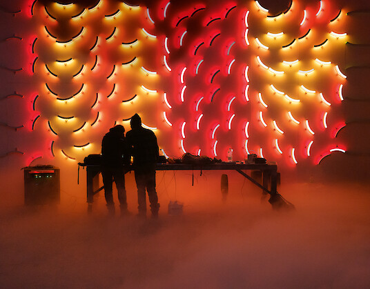 Liquid Tiles light installation with two people in front of the illuminated wall.