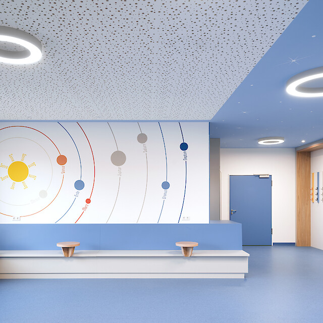 Wartebereich im Krankenhaus mit blauer Raumgestaltung und Ringleuchten an der Decke.