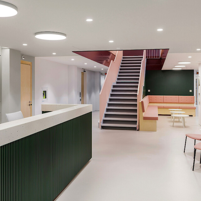 Reception and waiting area of a medical practice with circular ceiling luminaires and colourful accents.
