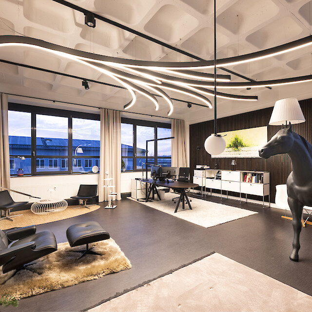 Oficina de ambiente residencial de Lichtagentur Bamberg con líneas de luz ramificadas en forma de árbol, zona lounge y una llamativa escultura de caballo.