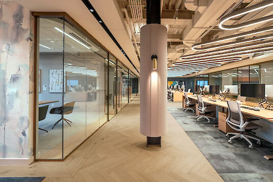 Oficina moderna en Boston con salas de reuniones acristaladas, puestos de trabajo abiertos y luminarias suspendidas curvas Liquid Line PX.