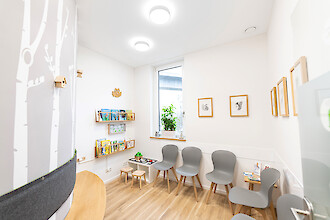 Child-friendly waiting area with forest motifs, books and Basic X1 luminaires.