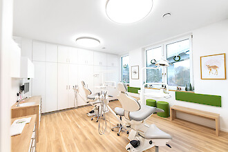 Bright orthodontic treatment room with two chairs and circular Basic X1 luminaires.