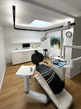 Dental treatment room with black dental chair and suspended Liquid Line PX.