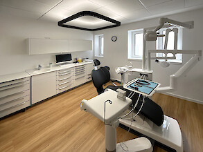 Dental treatment room with black dental chair and suspended Caleo PX.