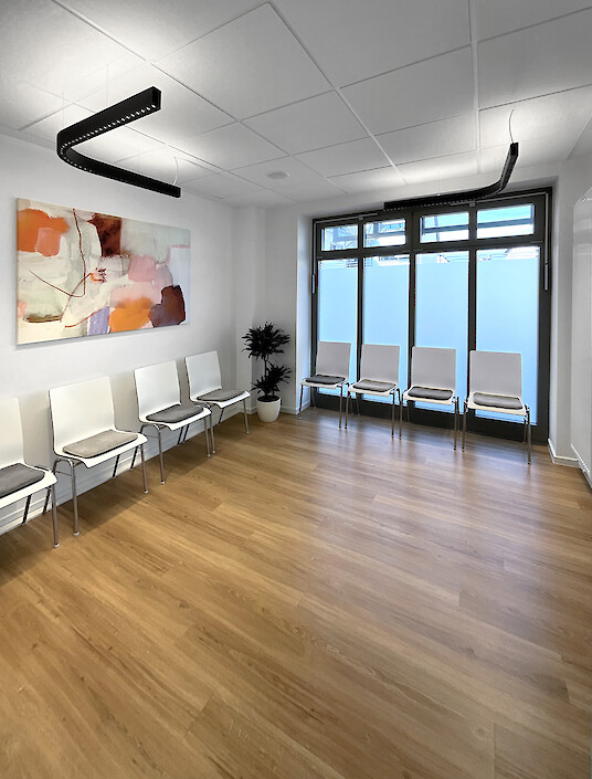 Practice waiting area with white chairs, wood flooring and suspended Liquid Line PX.