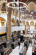 Moderne Buchhandlung in umgebauter Kirche mit hohen Bögen, Glasfenstern und großen, ringförmigen Pendelleuchten.