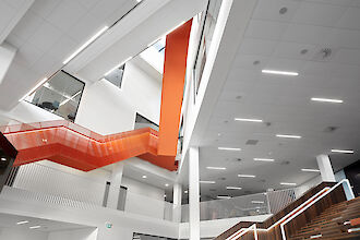 Innenansicht des Hafenzentrums in Århus mit Matric F5 Einbauleuchten und einer orangefarbenen Treppe in einem hohen Treppenhaus.
