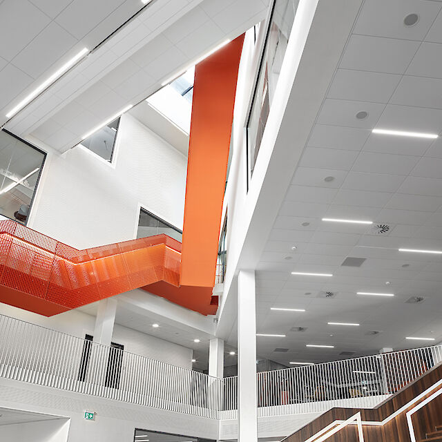 Innenansicht des Hafenzentrums in Århus mit Matric F5 Einbauleuchten und einer orangefarbenen Treppe in einem hohen Treppenhaus.