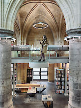Biblioteca moderna de arquitectura gótica con plataforma flotante de cristal y luminaria suspendida en forma de anillo