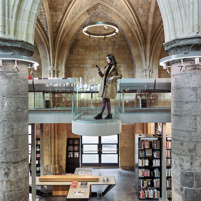 Biblioteca moderna de arquitectura gótica con plataforma flotante de cristal y luminaria suspendida en forma de anillo