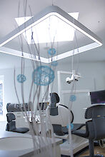 Zahnarztpraxis mit ergonomischen Stühlen und großer, rechteckig-linearer LED-Pendelleuchte Caleo von Lightnet.