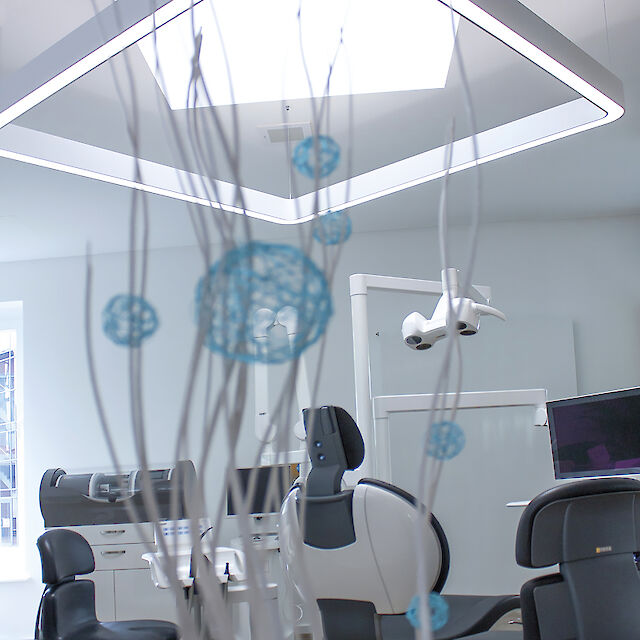 Zahnarztpraxis mit ergonomischen Stühlen und großer, rechteckig-linearer LED-Pendelleuchte Caleo von Lightnet.