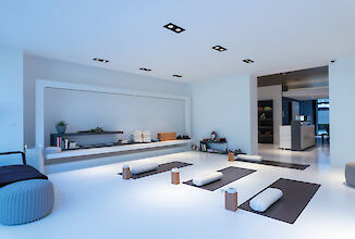 Luminoso y moderno estudio de yoga con esterillas, cojines de meditación y focos LED negros empotrados.
