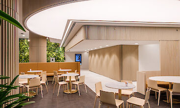 Moderno salón con mesas redondas, paneles de madera e iluminación lineal en el techo.