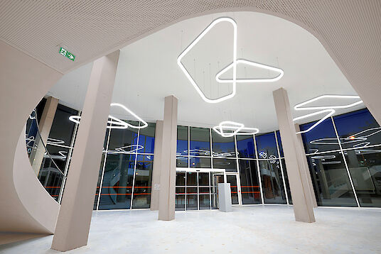 Foyer with high ceiling, extensive glazing and organically shaped Liquid Line pendant luminaires.