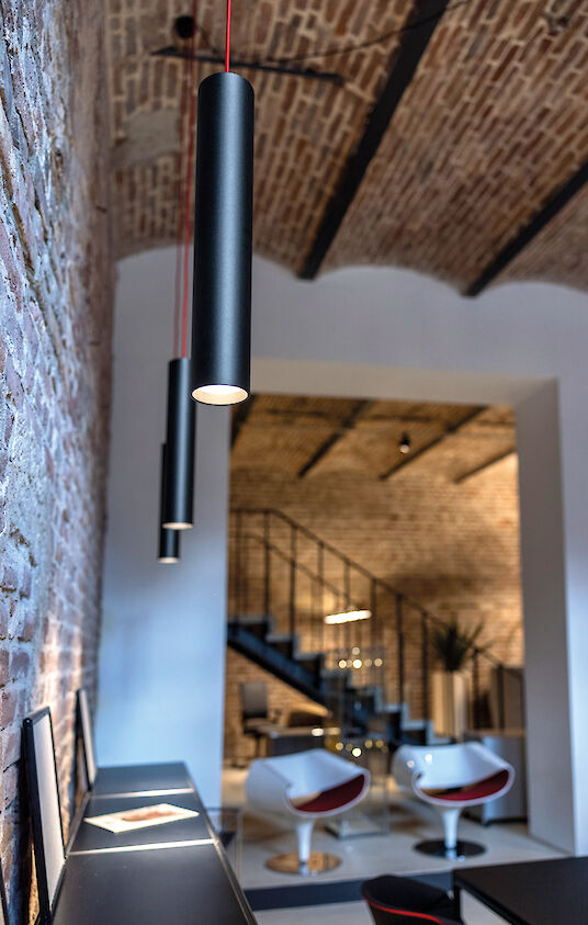 Office with tiled ceiling, black ‘Midpoint’ spotlights and white designer chairs.