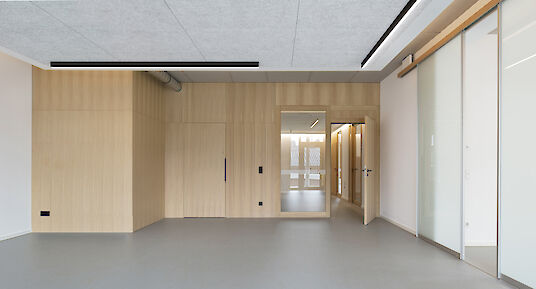 Room with wood panelling, sliding glass doors and black Matric surface-mounted luminaires on the ceiling.