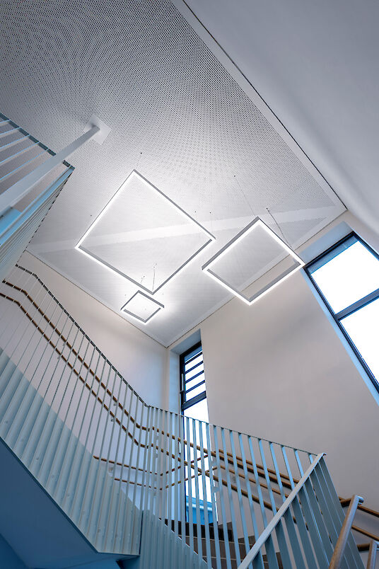 Staircase with high windows and three square Matric pendant luminaires on the ceiling.