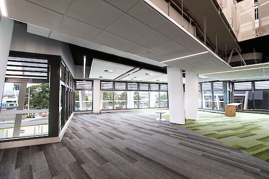 Open-plan office space with textured carpet, glass façade and linear Matric recessed luminaires.