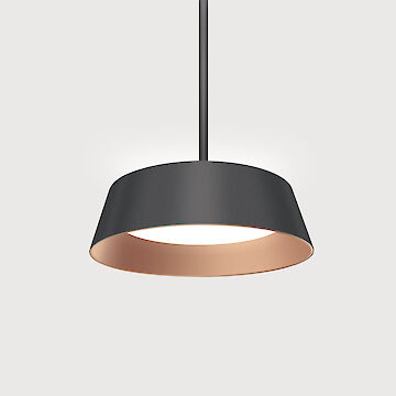 A modern pendant luminaire with a black, conical luminaire shade. The inside of the luminaire shade is copper-coloured, which creates a warm light. The luminaire hangs on a thin, black cable in front of a neutral grey background.