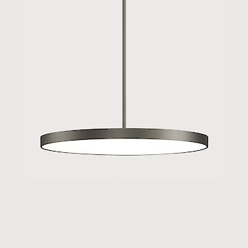 The picture shows a modern, round pendant luminaire with a flat, grey housing. The luminaire has a minimalist design and hangs from the ceiling on a cable. The background colour of the picture is a light grey.