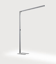 Un lampadaire fin et moderne au design minimaliste. Il a une forme en L et se compose d'un support métallique étroit et d'un bras de lampe horizontal. Le pied du luminaire est rectangulaire avec une découpe en U et s'adapte au style général. Le luminaire est placé sur un fond gris neutre.
