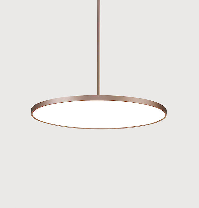 Minimalist, round pendant luminaire with a thin, bronze-coloured frame that shines in a neutral white. The luminaire is suspended from a narrow rod and is set against a neutral, light grey background.