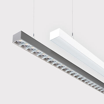 The picture shows a section of two linear pendant luminaires, one with a white and one with a grey surface. The underside of the grey luminaire is fitted with a silver-coloured lenticular louvre, with each lens containing a small LED light. The white luminaire has a smooth cover. Both luminaires have a modern design and are suspended from the ceiling on thin cables. The background is grey.