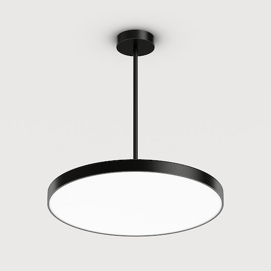 The picture shows a modern, round pendant luminaire with a flat, black housing. The luminaire has a minimalist design and hangs from the ceiling on a black cable. The background colour of the picture is a light grey.