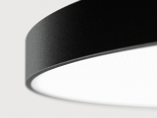 The illustration shows a section of a modern, round pendant luminaire with a flat, black housing. Only one half of the luminaire can be seen. The background colour of the picture is a light grey.