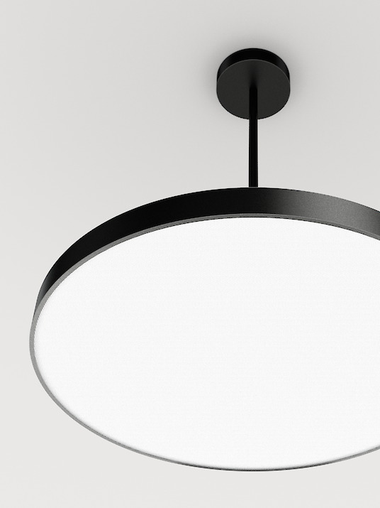 The illustration shows a section of a modern, round pendant luminaire with a flat, black housing. The section shows the underside of the light so that the diffuser of the luminaire can be recognised. The background colour of the image is a light grey.