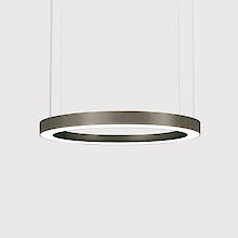 Moderna luminaria colgante en forma de anillo con un fino marco gris. La luminaria está suspendida de finos cables y emite una luz suave y difusa hacia abajo. El fondo es gris liso y atrae la mirada hacia la elegante luminaria.