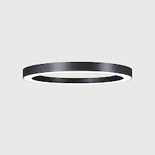 The picture shows a modern, ring-shaped surface-mounted luminaire that emits a diffuse, soft light downwards. The surface of the luminaire has a matt black texture. The background of the picture is a uniform light grey.