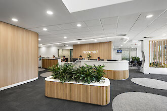 Reception area with wood and white accents, curved reception desk and planted room divider in the foreground.