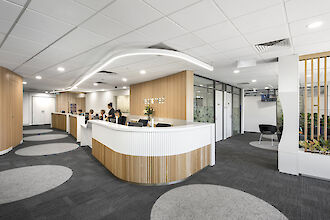 Reception area with reception desk, wood and white accents and a curved light line.
