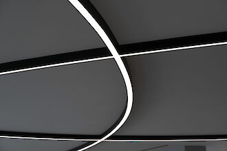 Curved Liquid Line lines of light in a black and white look run across a ceiling.