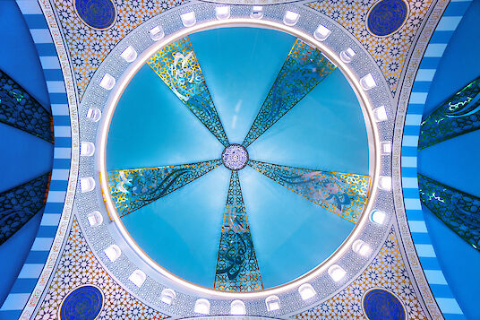 Blue dome of the Ulu Mosque with golden ornaments and large ring-shaped Ringo Star pendant light.