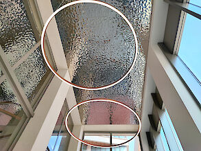 Dos anillos de LED iluminados delante de un techo estructurado en un moderno edificio inundado de luz