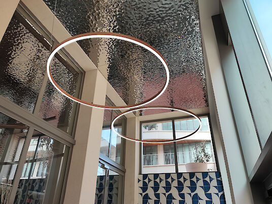 Dos anillos de LED iluminados en un techo estructurado de un edificio moderno inundado de luz