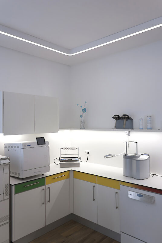 Zone de préparation avec technique médicale, éclairage Caleo Inverse en saillie et armoires à code couleur.