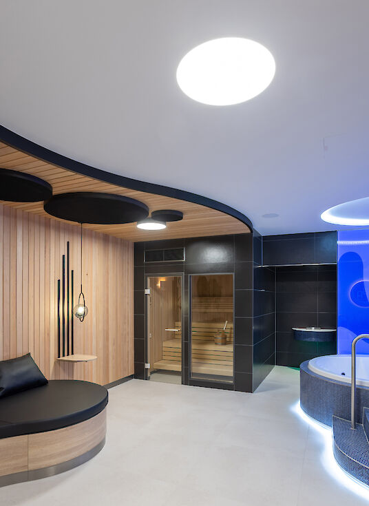 Spa area with sauna, whirlpool, round bench and round Basic ceiling luminaires.